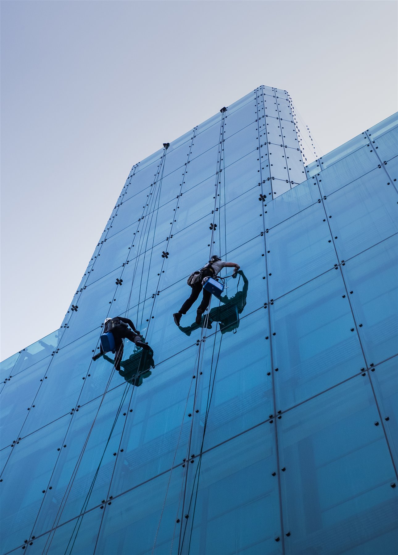 Rope access technicians working safely on a glass building